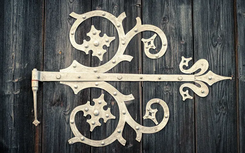 ornate wrought-iron hinge mounted on a wood barn-style door panel