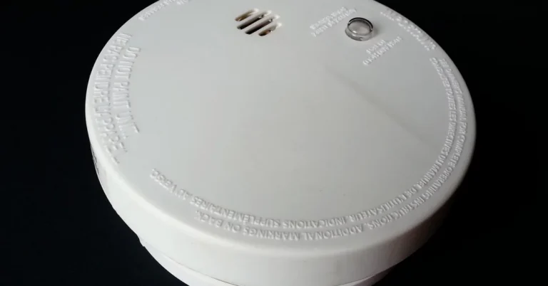Ceiling-mounted smoke detector with red light sensor visible