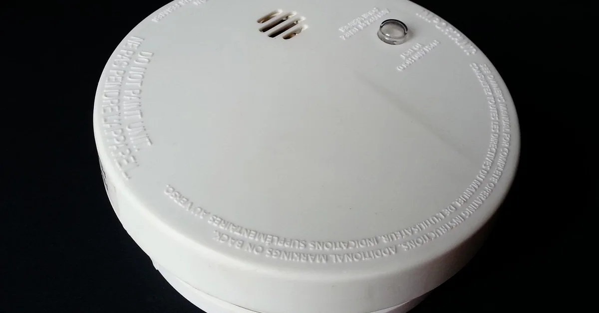 Ceiling-mounted smoke detector with red light sensor visible