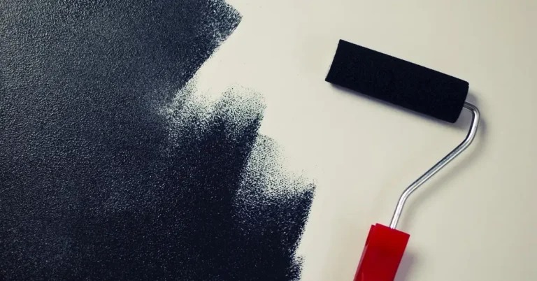 Paint roller loaded with black paint on a white surface