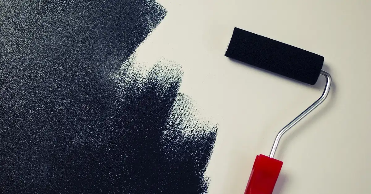Paint roller loaded with black paint on a white surface