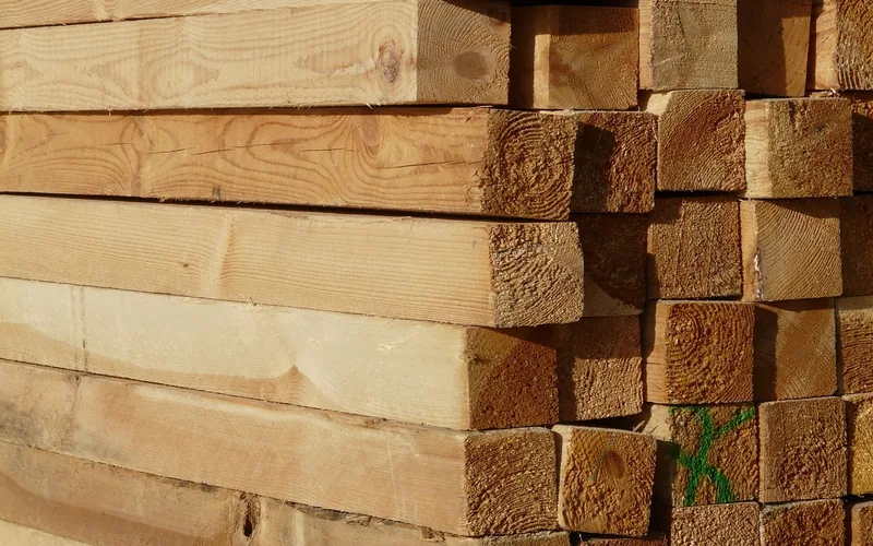 stacked dimensional lumber boards with a green grading mark at a storage yard