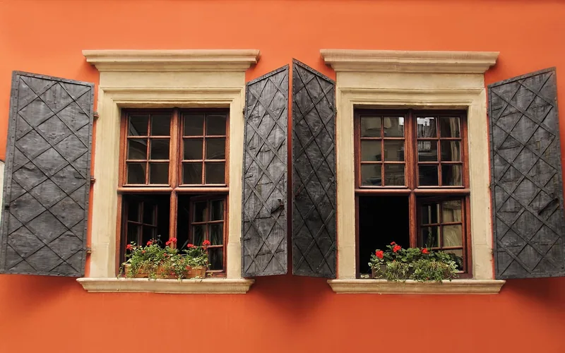 exterior wood window frames with shutters on a house facade, a common rot-prone trim area