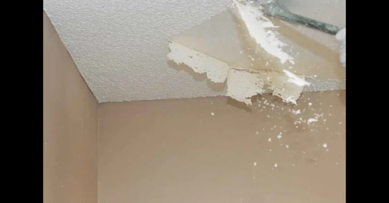 Putty knife scraping a section of painted popcorn ceiling texture down to the drywall