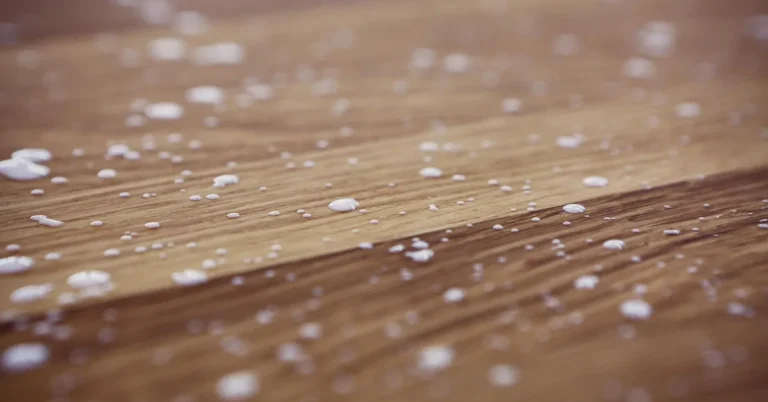 dried white wood glue drips scattered across a wood plank surface