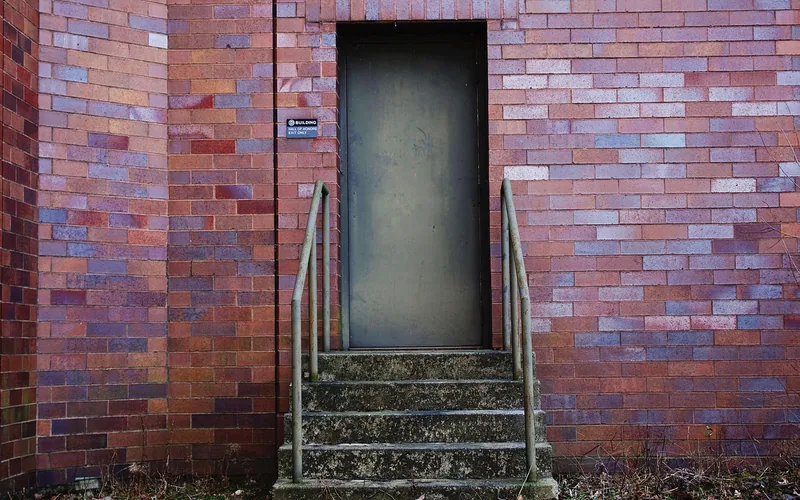 worn concrete entry steps with metal handrails leading to a door worn concrete entry steps with metal handrails leading to a door