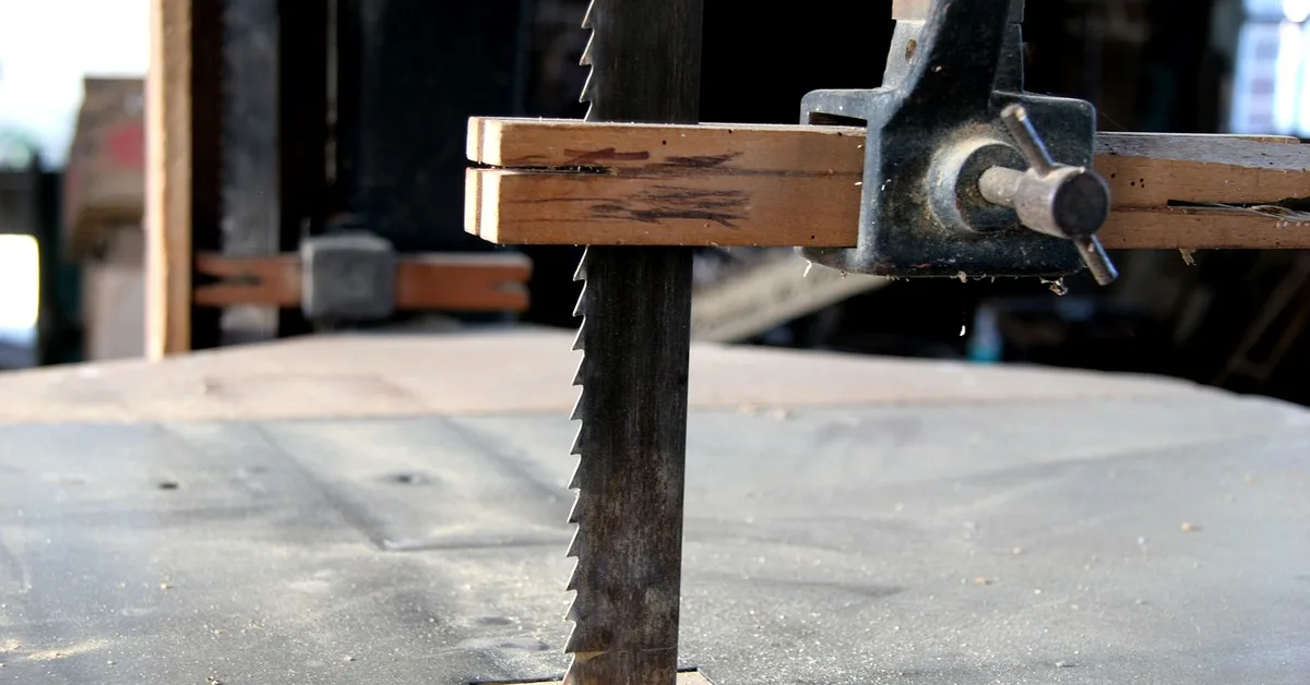 Close-up of an antique bandsaw blade set into a worn cast-iron table