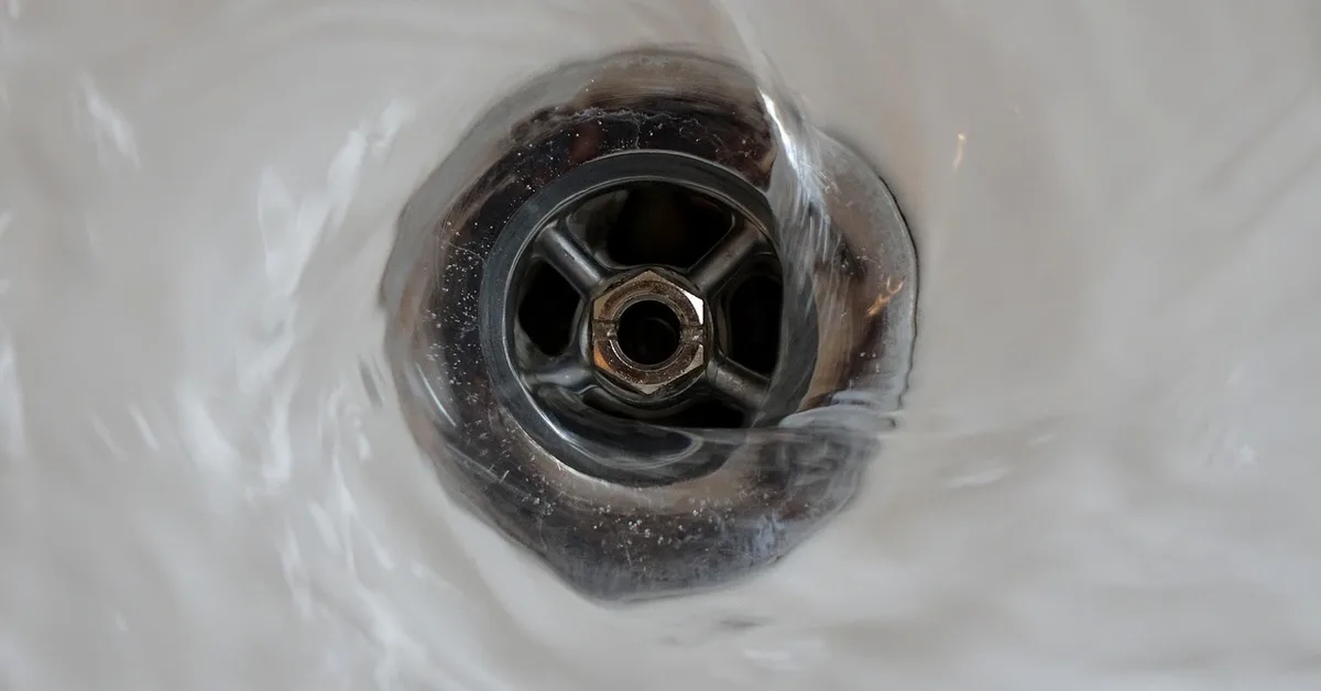 Water swirling down a bathtub drain with a crossbar strainer
