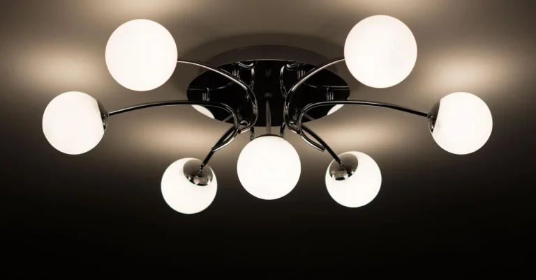 Multi-arm ceiling light fixture with white globe shades mounted and illuminated