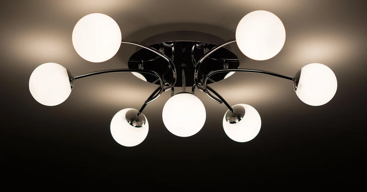 Multi-arm ceiling light fixture with white globe shades mounted and illuminated