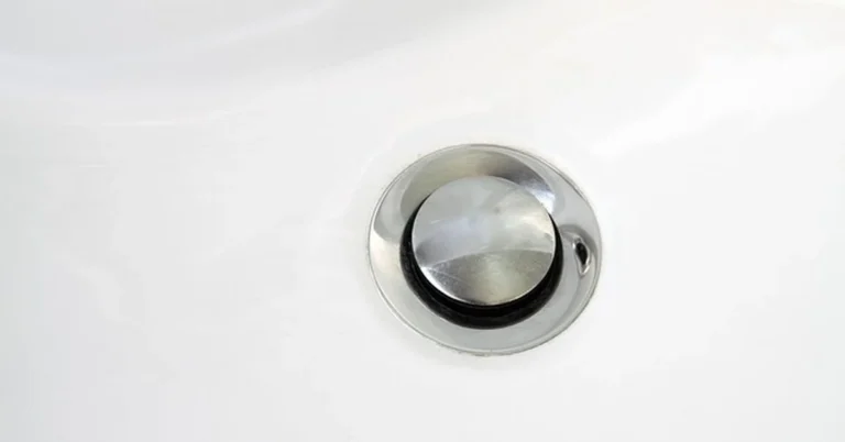 Chrome pop-up drain stopper in a white bathroom sink