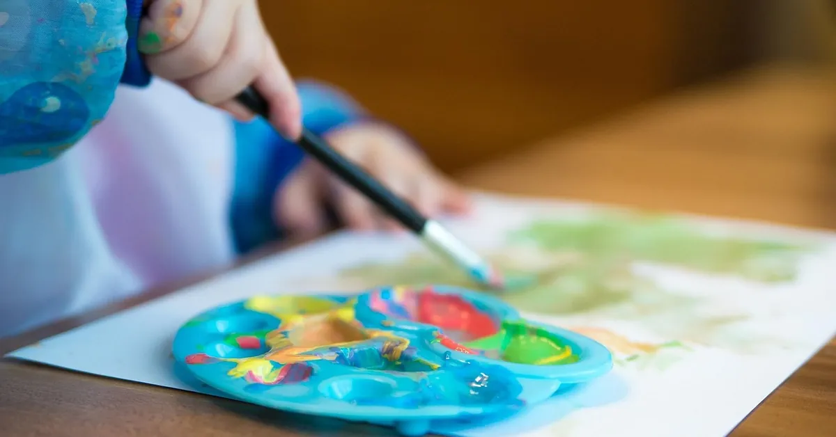 Child painting a wooden craft kit at a table