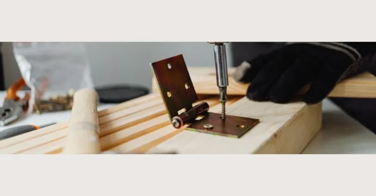 Drilling a screw into a door hinge on a wood panel closeup