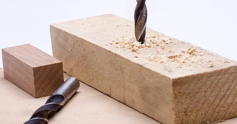 drill bit boring a clean hole into a wood block with visible wood shavings