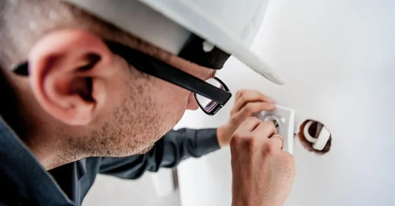 Electrician working on a wall outlet junction box for a plug-in light conversion