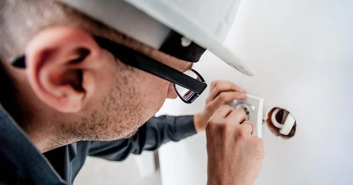 Electrician working on a wall outlet junction box for a plug-in light conversion