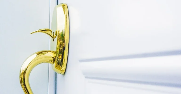 Gold door handle and knob set mounted on a white painted door