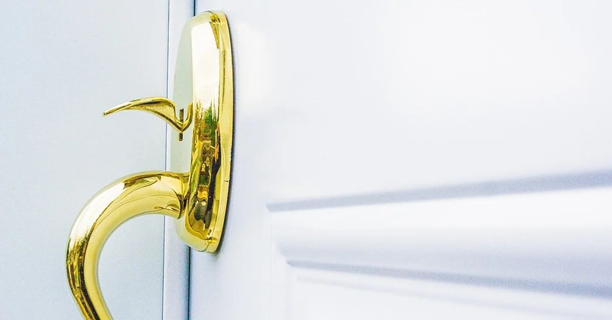 Gold door handle and knob set mounted on a white painted door