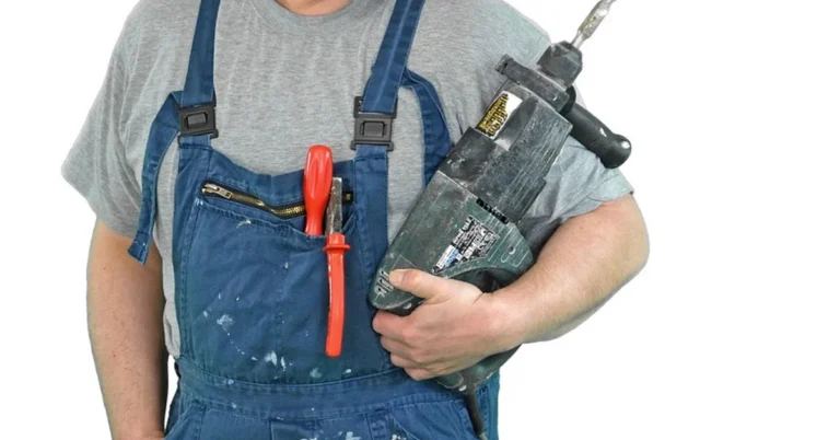 Worker holding a hammer drill with masonry bit used for drilling concrete