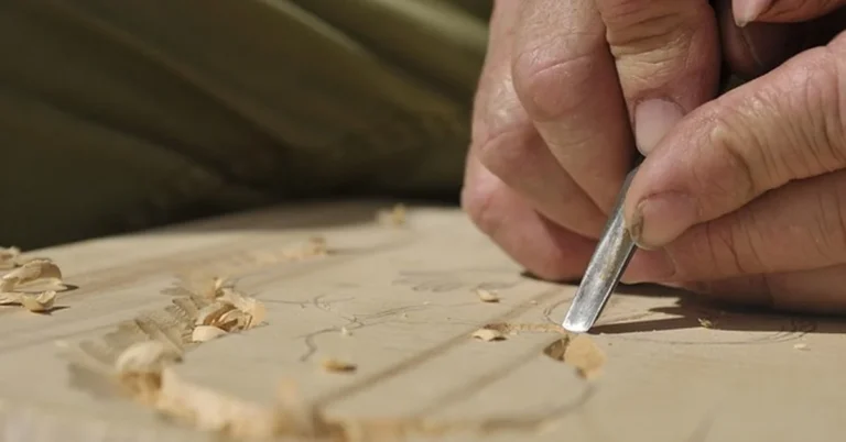 Hand using a wood chisel to carve out a recess