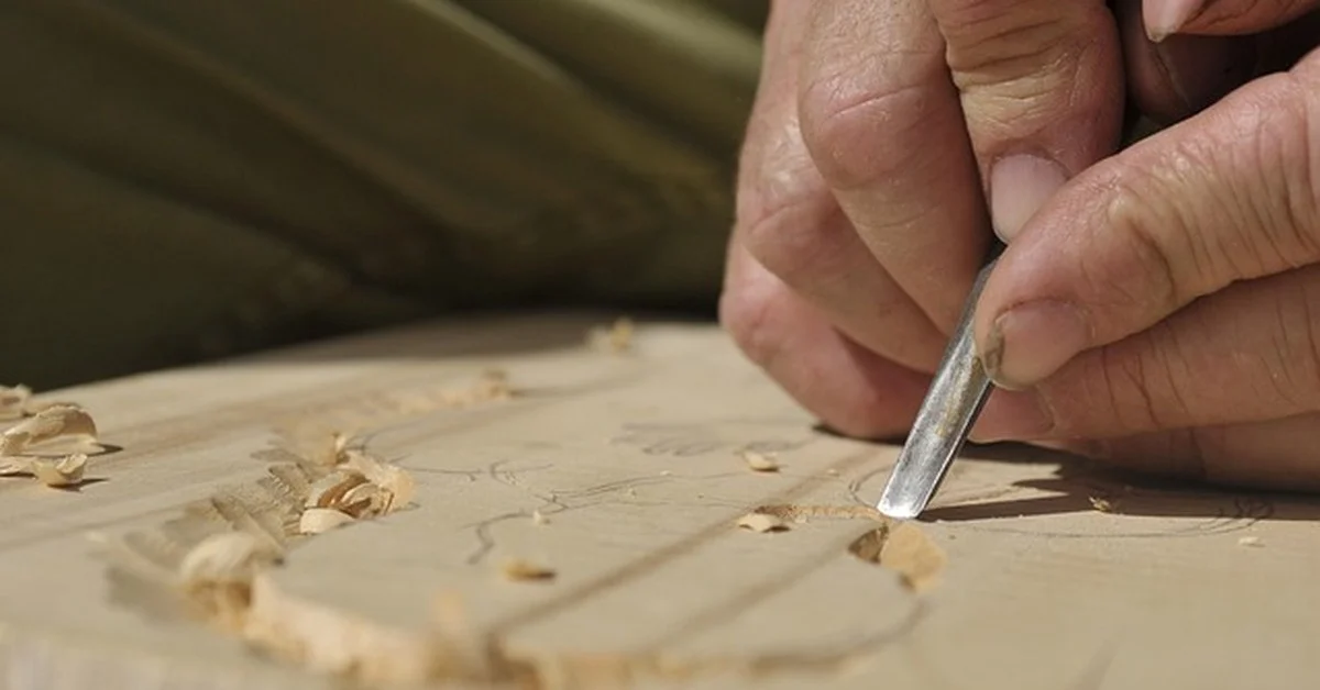 Hand using a wood chisel to carve out a recess