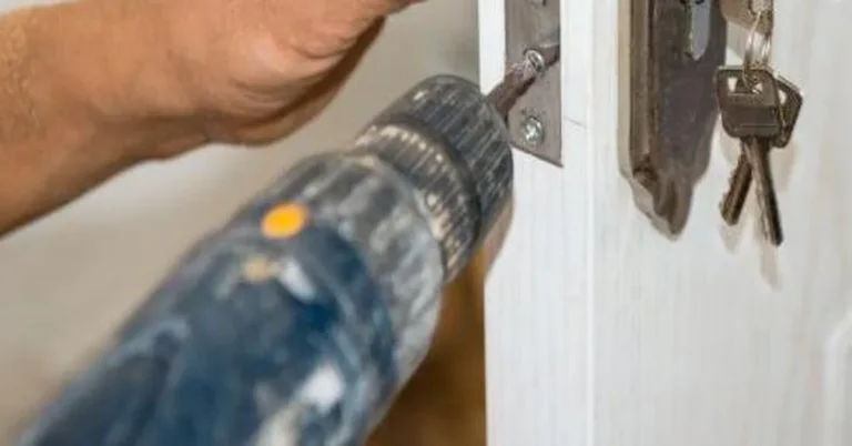 Drilling the edge hole for a deadbolt with a cordless drill, hardware and keys on the door