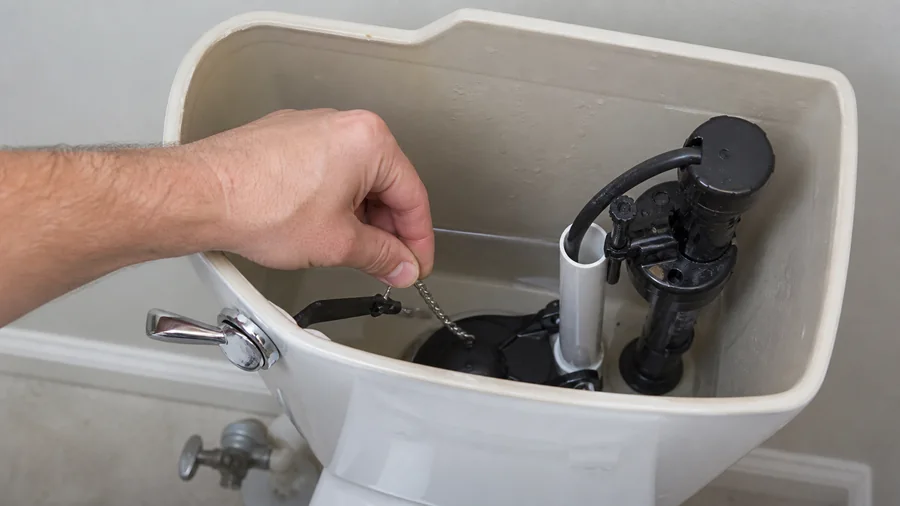 Open toilet tank showing flush handle, lift chain, flapper, and water level during a stuck flush check