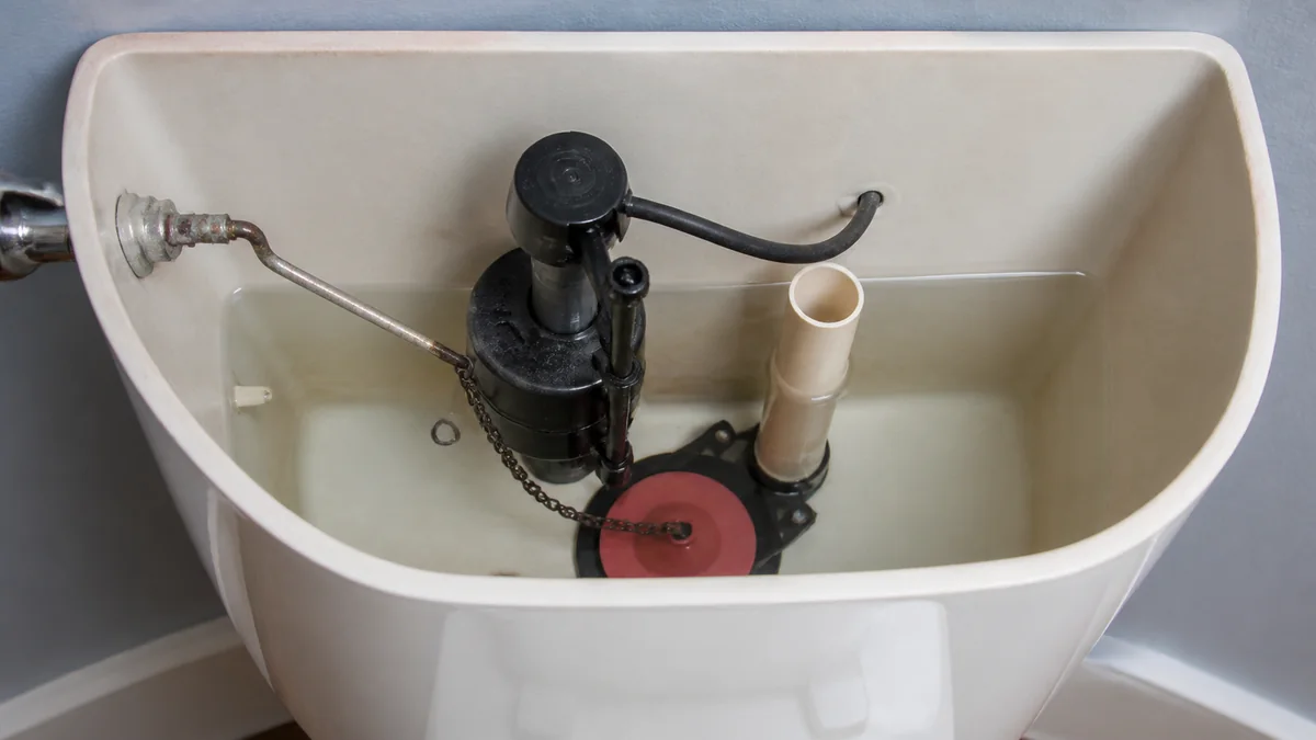 Open toilet tank showing flush handle, lift chain, flapper, and water level during a stuck flush check