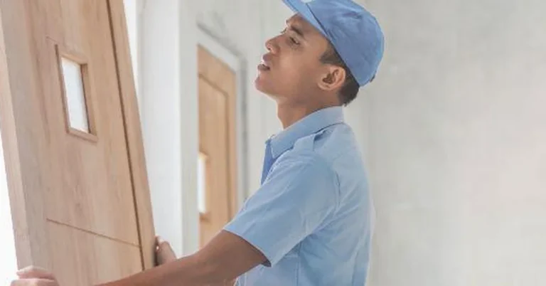 Man installing a wood shed door into the frame