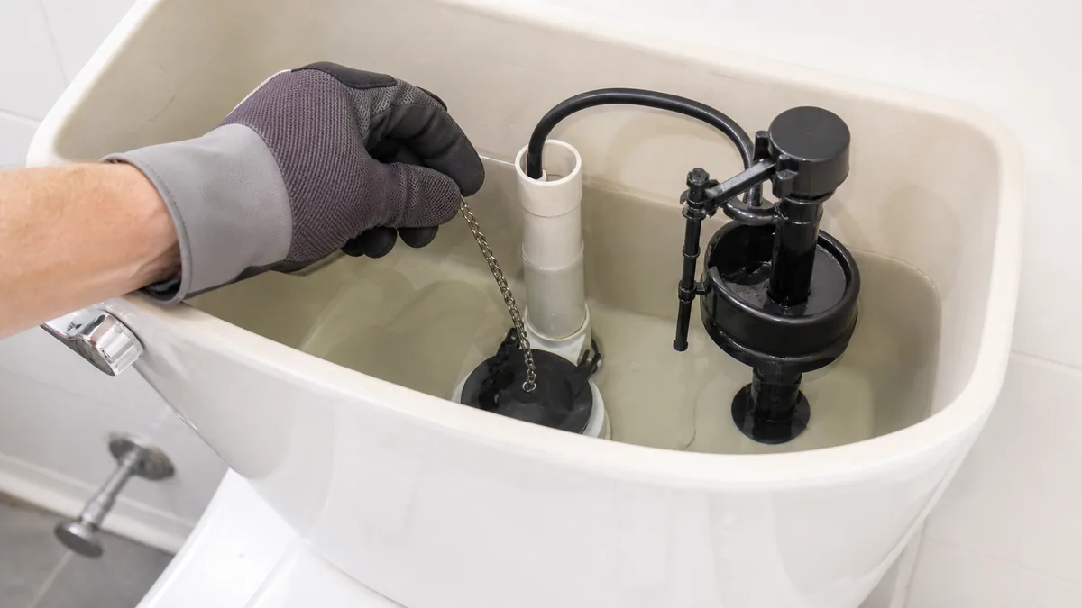 Toilet tank repair showing a flush seal, fill valve, and water-level check for a running toilet