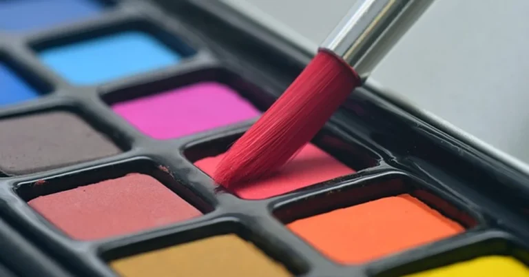 mixing red paint on a palette with a brush