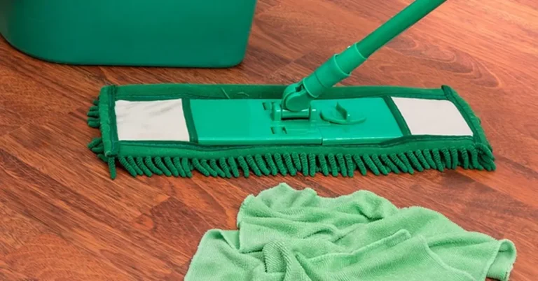 Green microfiber mop and cloth cleaning a hardwood floor to remove black stains