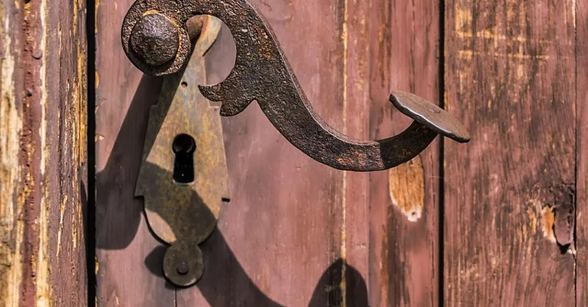 Old worn metal door handle with visible rust and wear
