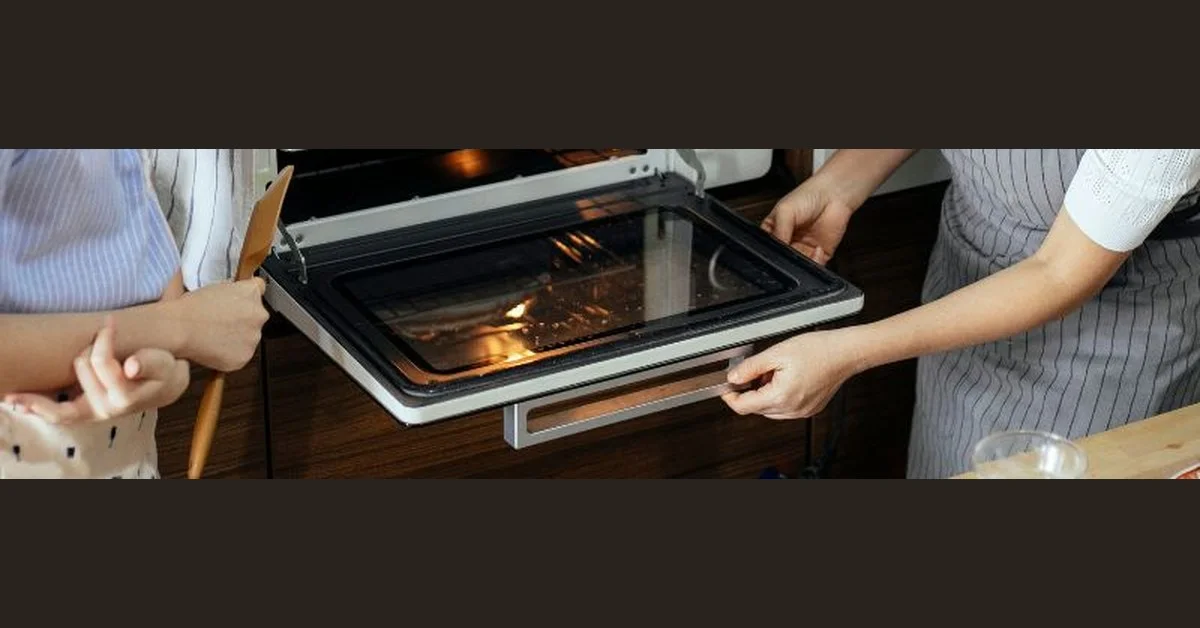 Oven door partially open at angle showing hinges before removal
