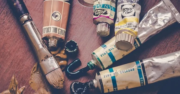 Paint tubes and brush with wet paint on a wooden surface