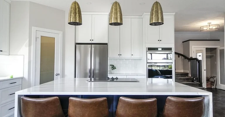 Gold pendant lights hanging at the correct 30-36 inch height above a white marble kitchen island