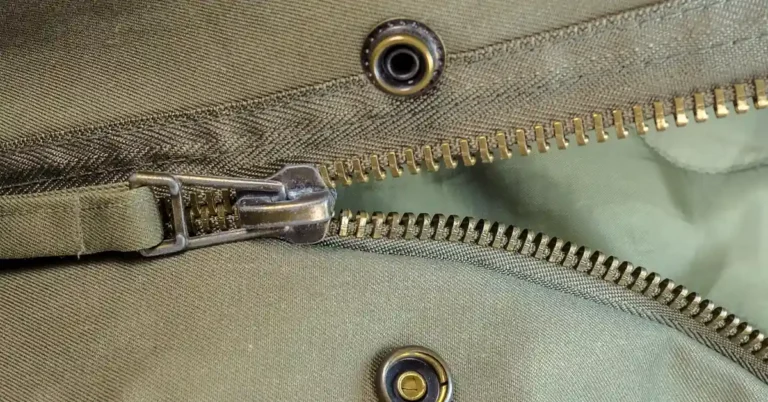 Metal popper fastener stud and socket riveted into a jacket seam near a zipper