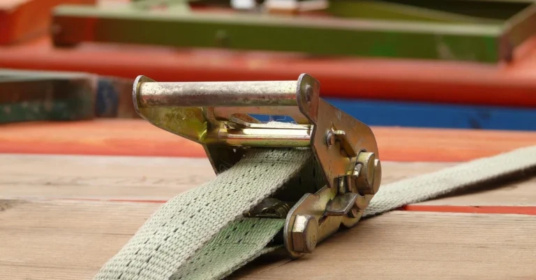 Ratchet strap tie-down buckle secured to a wood pallet
