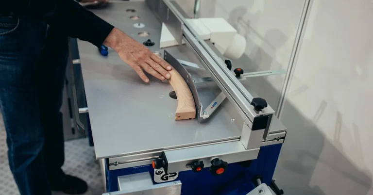 Woodworker guiding a piece through a powered cutting tool to shape a mortise