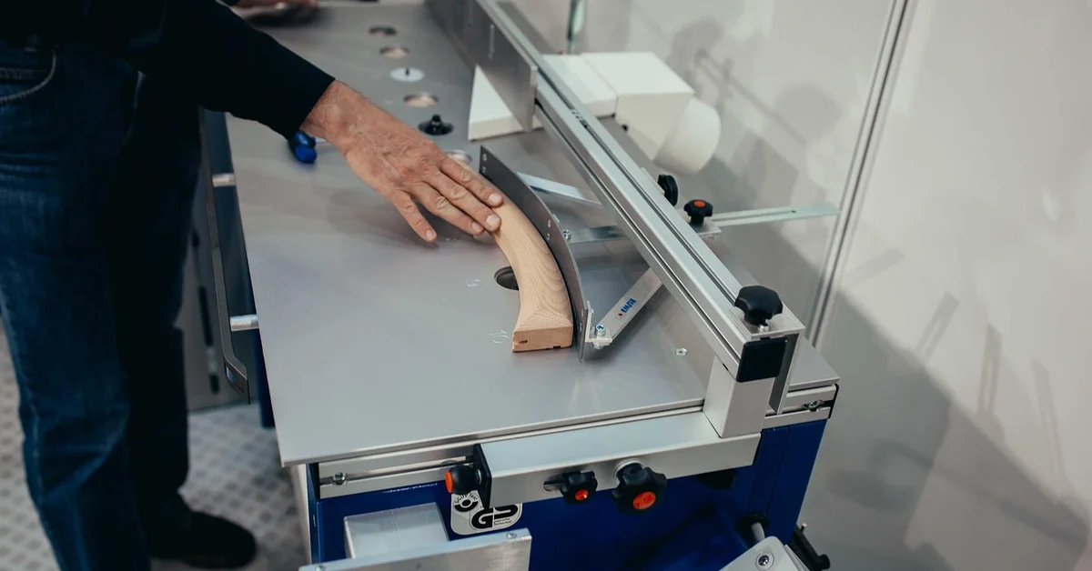 Woodworker guiding a piece through a powered cutting tool to shape a mortise
