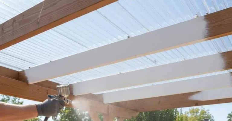 Person spray painting the underside of a clear polycarbonate roof panel