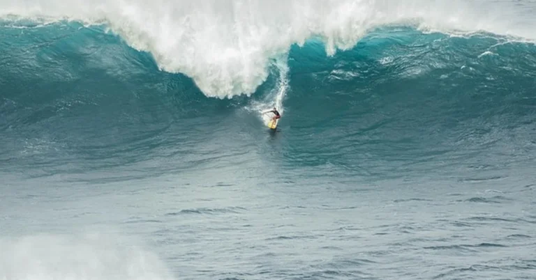Surfer riding a large ocean wave on a surfboard