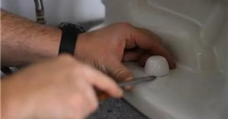 Hand tightening a toilet base bolt cap with a screwdriver