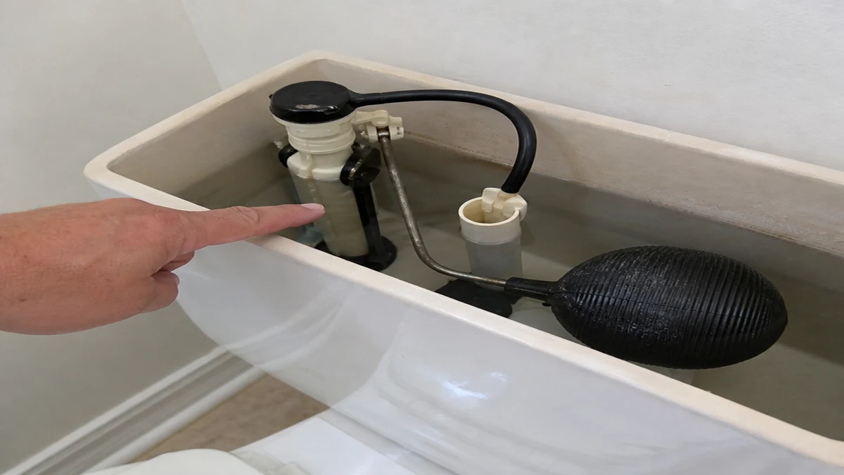 Ball-float toilet fill valve checked inside a running toilet tank