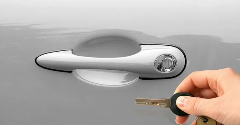 Hand unlocking a car door handle with a key