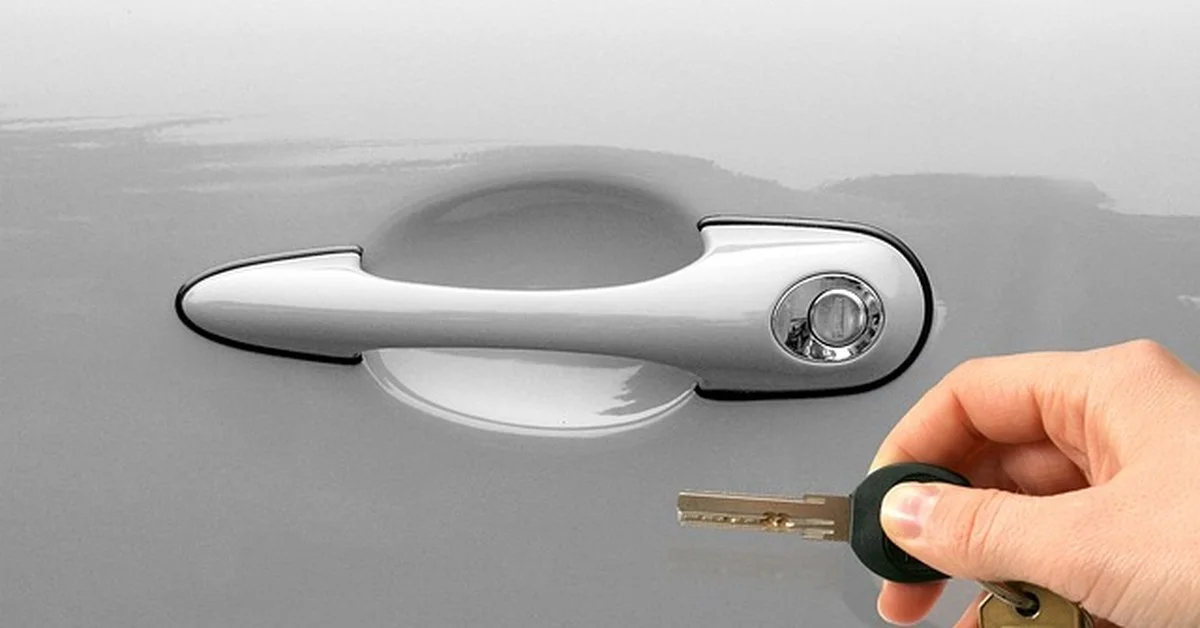 Hand unlocking a car door handle with a key
