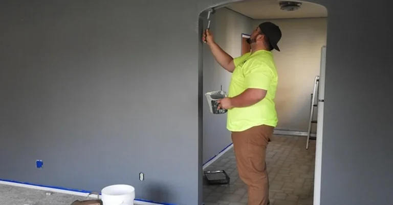 Painter smoothing and repainting a patched interior wall