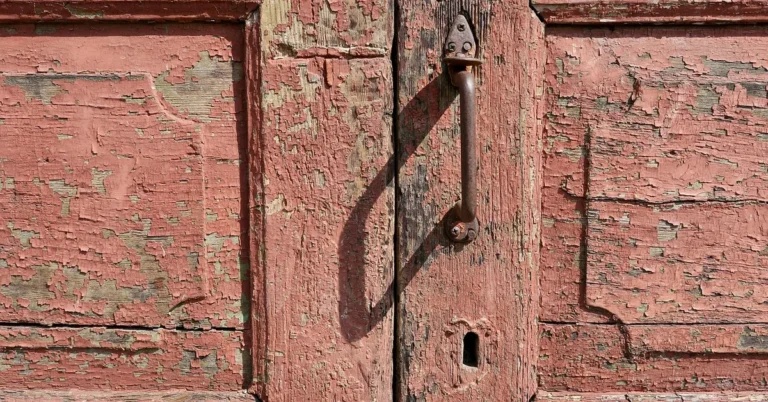 Close-up of a weathered wooden front door with peeling paint before restoration