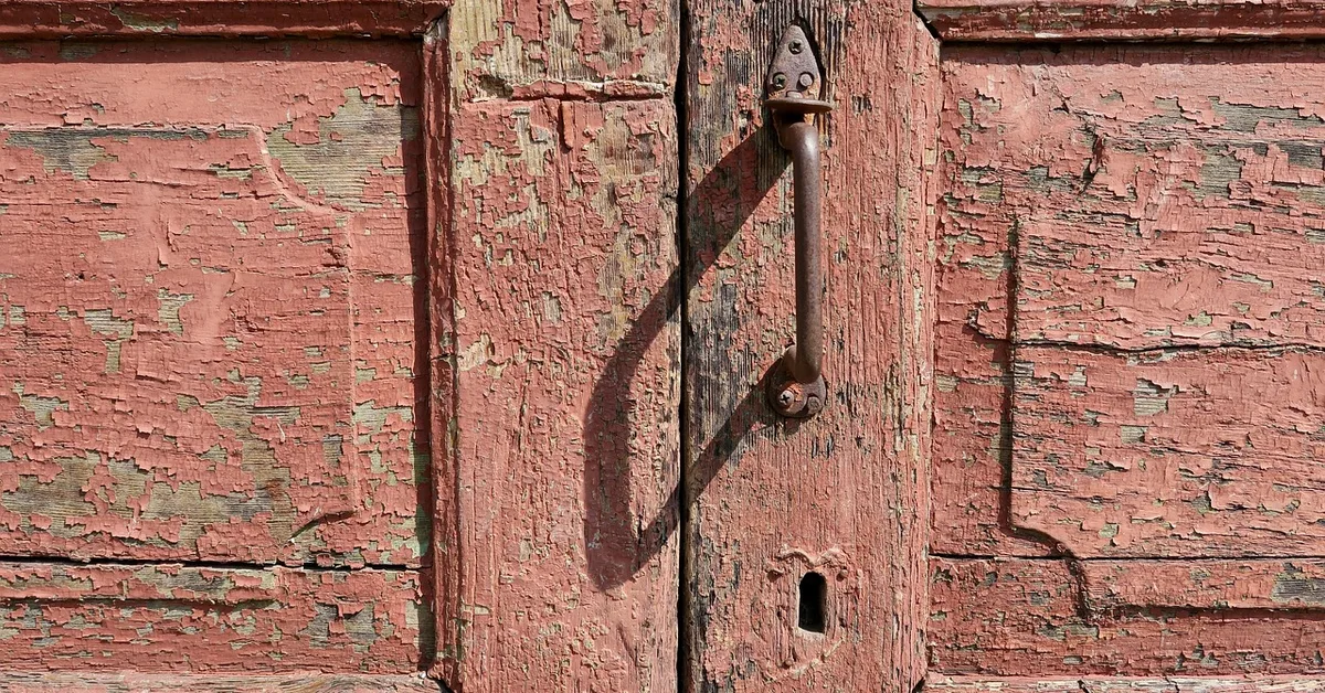 Close-up of a weathered wooden front door with peeling paint before restoration