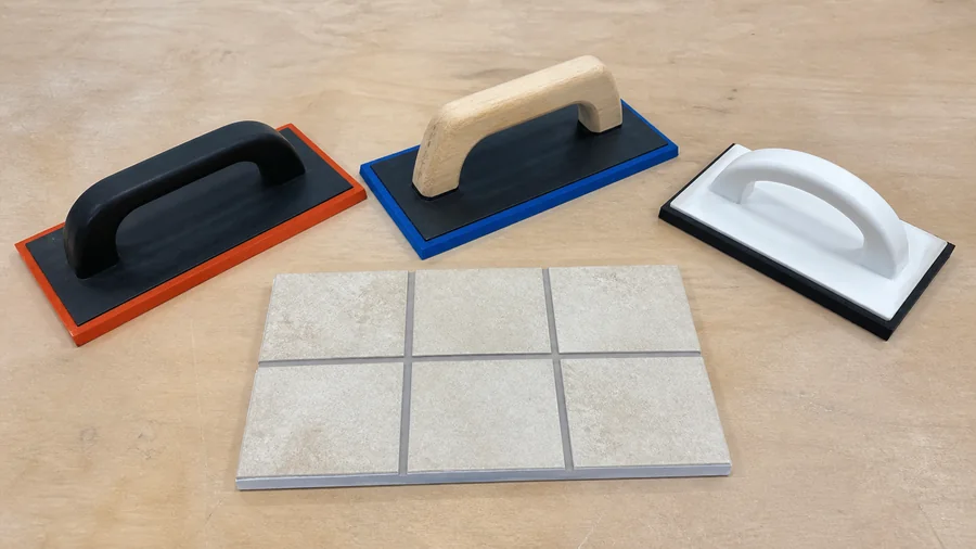 Rubber grout float spreading grout diagonally across ceramic tile joints